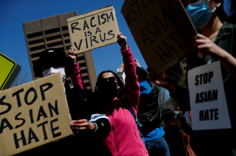 This image is three people holding up signs saying “Racism is a Virus” and “Stop Asian Hate”
