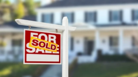 Photo of ‘For Sale’ sign marked ‘sold’ in front of a home.