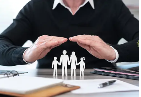 Photo signifying stable families with life insurance with an agent creating a roof with his hands above a family.