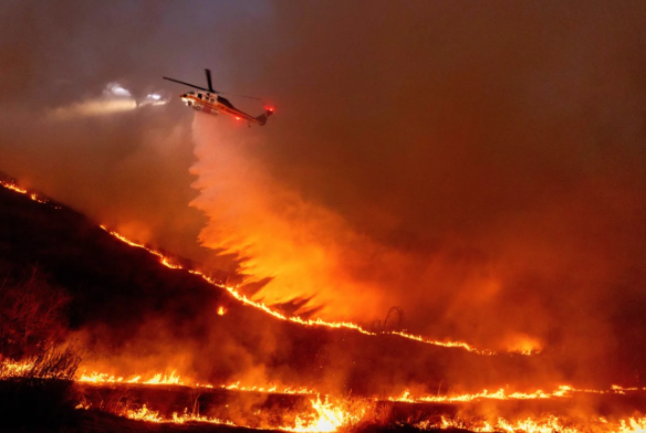 Ethan Swoop/AP (Picture of a helicopter dusting the fire to help control the spread.)