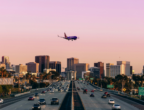 Photo of an airplane flying over a busy freeway.