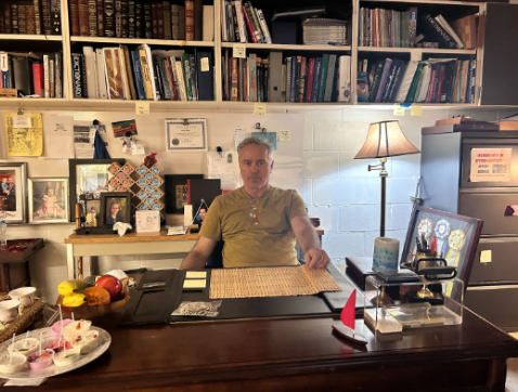 A photo of Mr. Booker sitting at his desk. 
