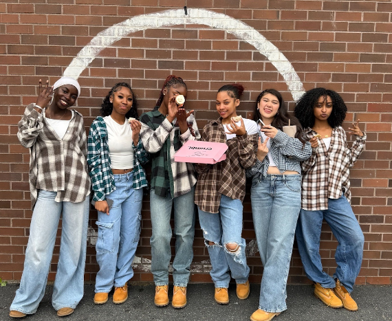 A picture of the Elite step team with a Crumbl cookie box.
