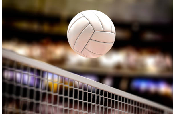 A photo of a volleyball going over a net