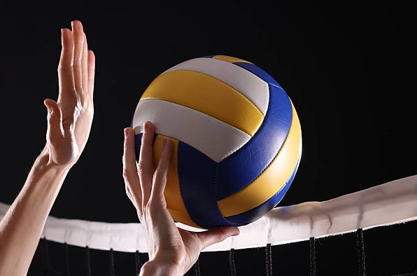A photo of someone hitting a volleyball over the net. 