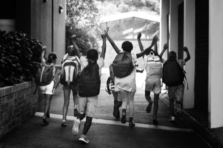 Photo of children leaving school with their backpacks on.
