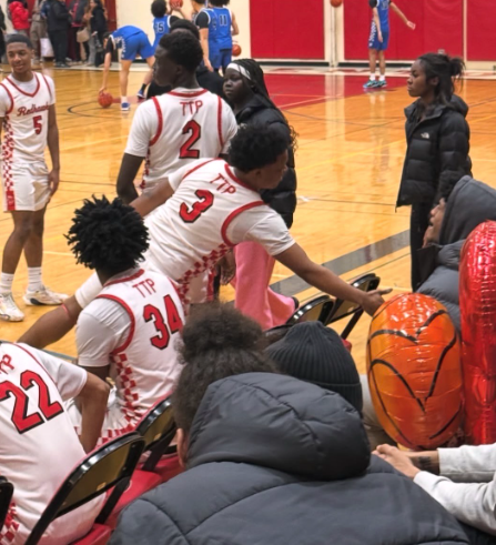Photo of senior guard Isaac Elegan high fiving someone on the sideline. 