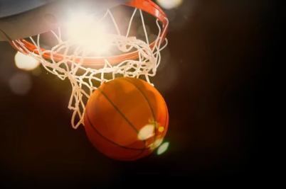 Photo of a basketball going into the hoop.