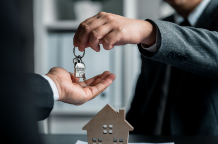 Photo of a real estate agent's hands handing over keys to a buyer's hands.